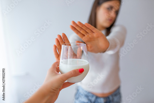 Close-up Of A Woman Rejecting Glass Of Milk At Home. Woman with milk allergy isolated. Lactose intolerance. Dairy Intolerant Woman refuses to drink milk photo