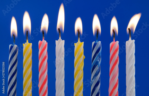 Burning colorful candles on blue background 