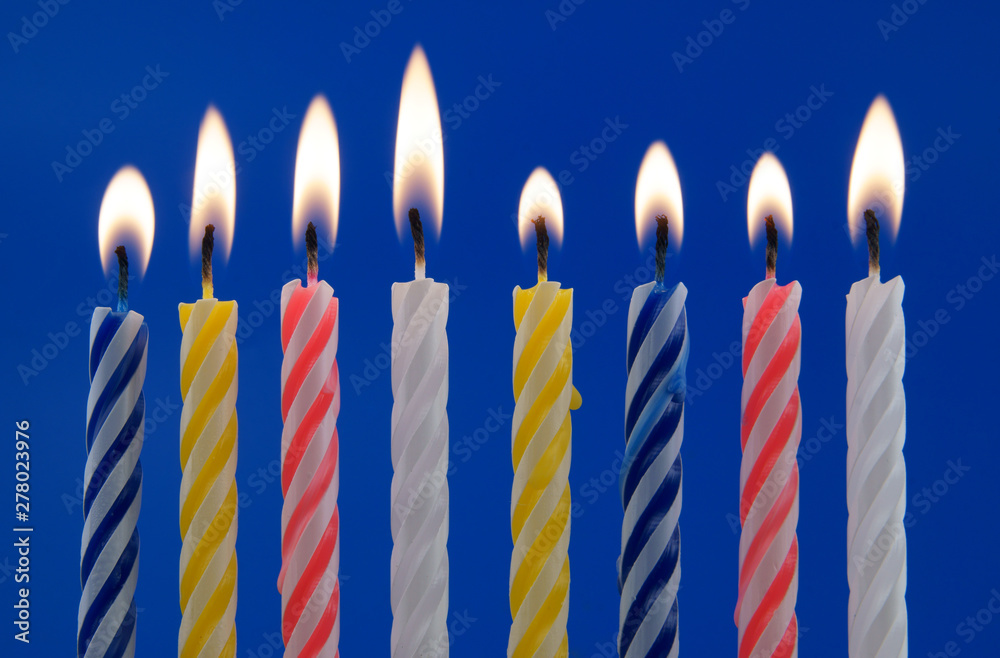 Burning birthday candles on blue background Burning birthday candles on blue background