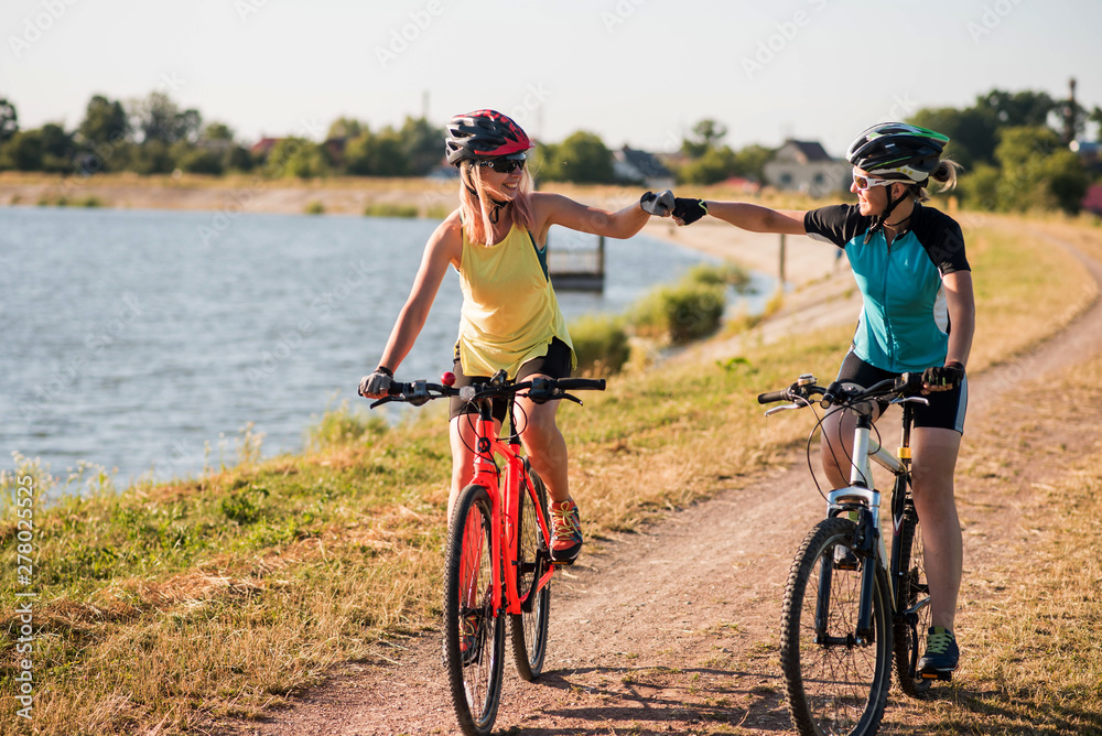 Women on bike riding by the lake shore outdoors at the park
