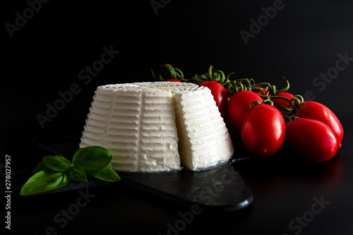 Tableau sur toile Front view view of fresh ricotta cheese with basil and cherry tomatoes on black plate italian food concept