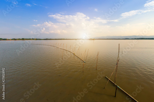 landscape of sunshine on lake or large swamp and mountains and blue dramatic sky with cloud at sunset at 