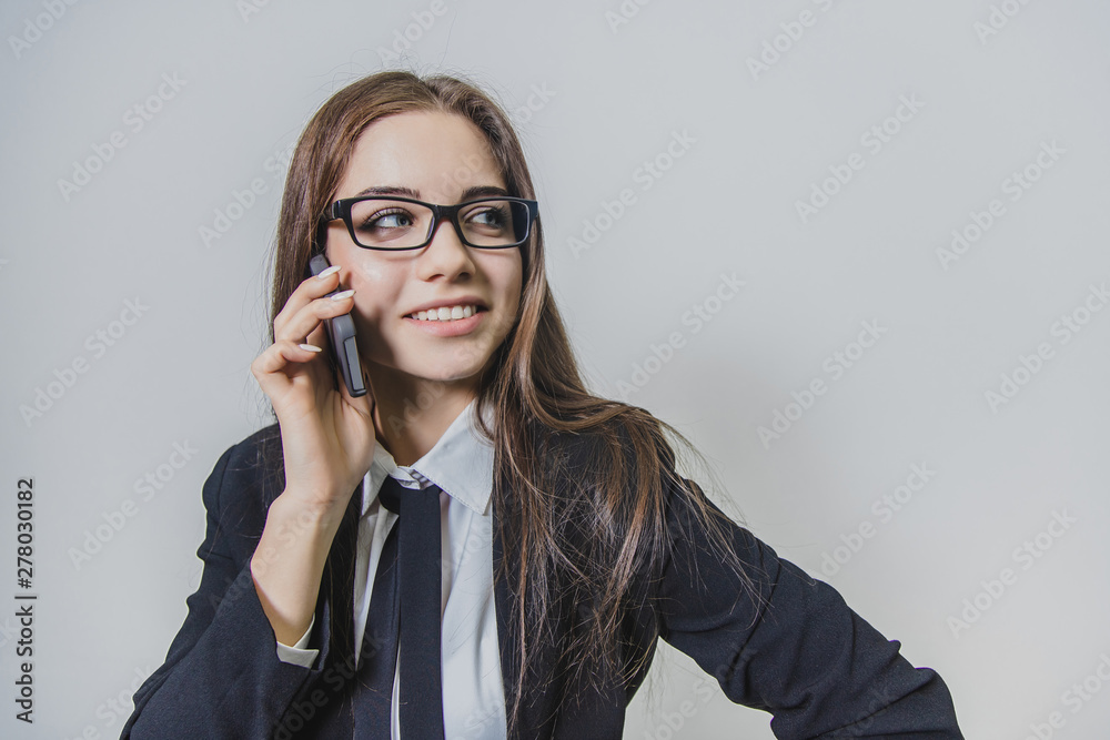 Calm pretty businesswoman is holding a phone in her hand and is talking, looking aside. Thoughtful busy lady. Calm pretty businesswoman is holding a phone in her hand and is talking, looking aside. Thoughtful busy lady.