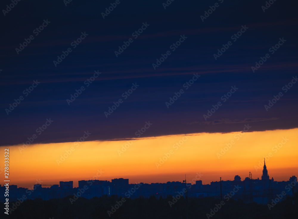 Dark cloudscape on sunset with stripe of the clear sky, over the panoramic silhouette of the buildings. Moscow city skyline, evening urban landscape. Dark cloudscape on sunset with stripe of the clear sky, over the panoramic silhouette of the buildings. Moscow city skyline, evening urban landscape.