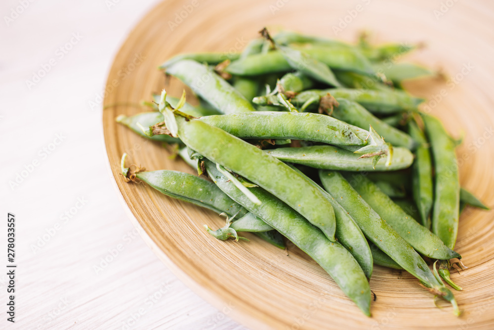 Peeled green peas in a wooden plate on a wooden table. Organic food. Peeled green peas in a wooden plate on a wooden table. Organic food.