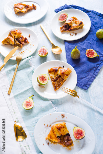 Figs galette made with pastry crust and fresh fig on a dish over a wooden board, top view.
