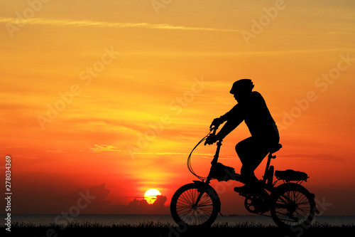 Silhouette Cycling on blurry sunrise sky background.