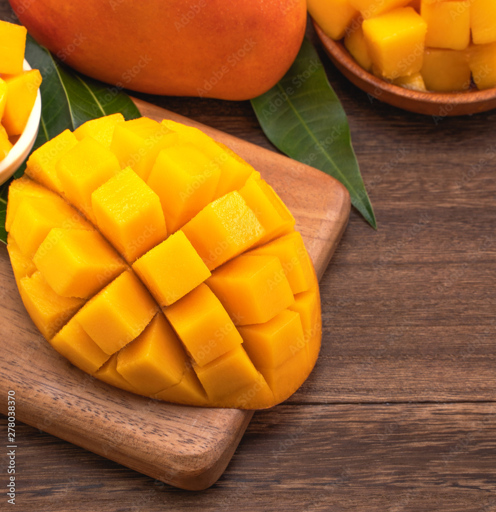 Fresh Mango - Juicy chopped mango cubes on wooden cutting board and rustic timber background. Tropical summer concept. Close up, macro, copy space.