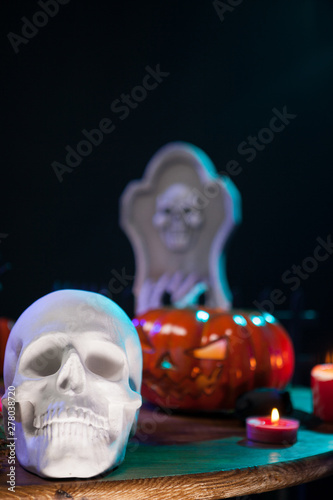 Creepy human skull with other halloween decorations on a wooden table