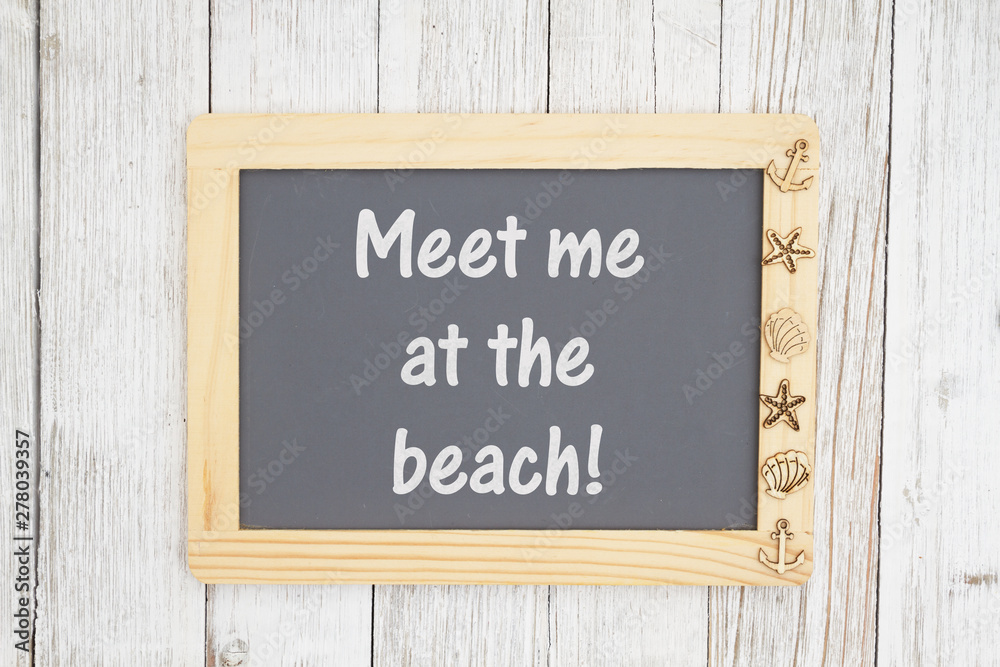 Meet me at the beach text on a chalkboard with nautical objects