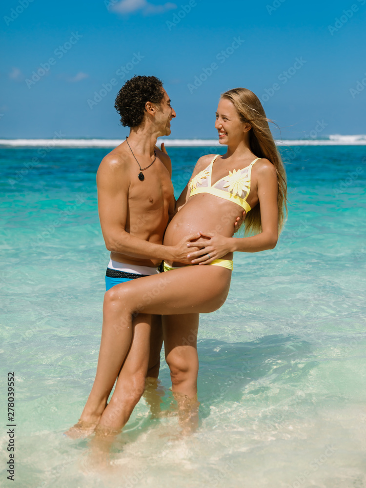 Happy pregnant woman with husband expecting baby at tropical beach Happy pregnant woman with husband expecting baby at tropical beach