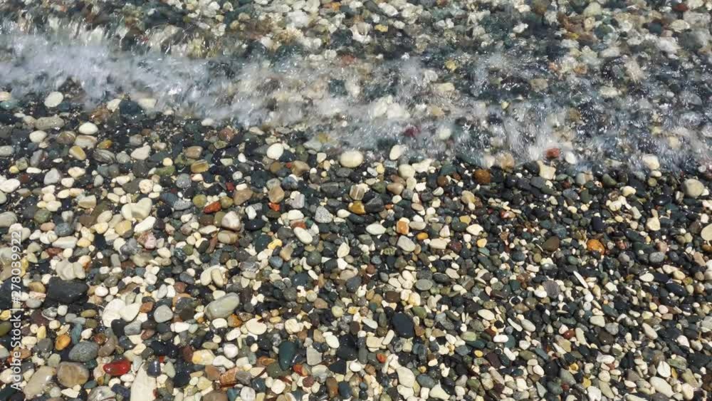 View of blue Mediterranean sea with pebbles. Close up of seawater waves splashing against small rocks at surf View of blue Mediterranean sea with pebbles. Close up of seawater waves splashing against small rocks at surf