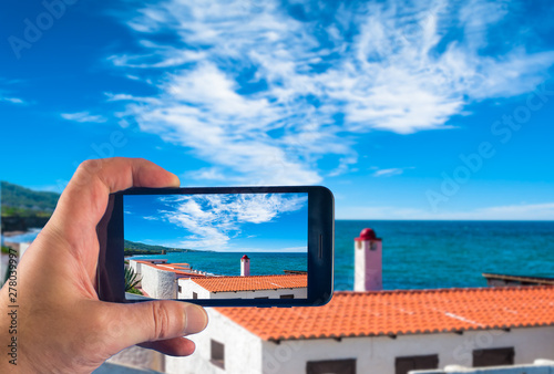 Hand with smartphone taking pictures in a sunny day on the sardinian coast