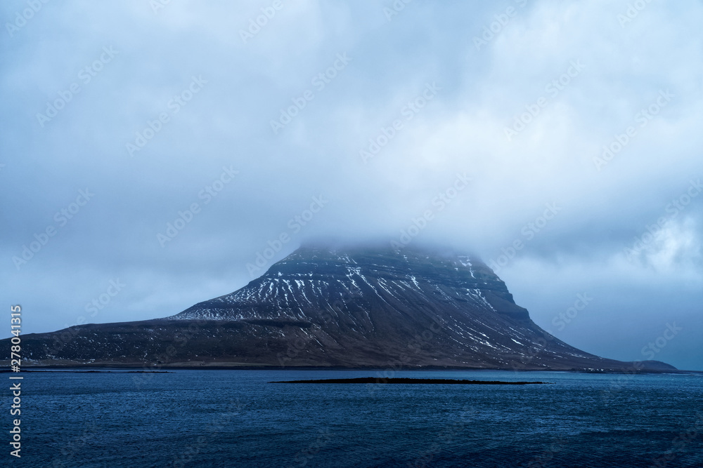 Kirkjufell mountain in Iceland with mystical cloudy atmosphere from alternative perspective as usual