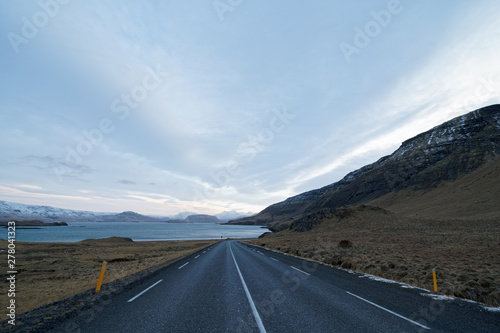 On the road along a lake in Iceland with clouded sky and mystical atmosphere in winter
