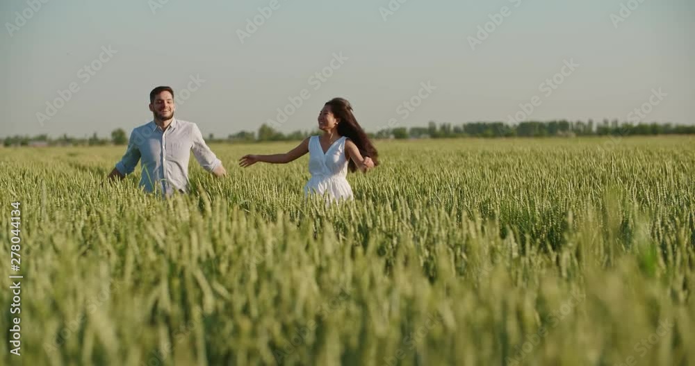 Cute interracial couple in love running through wheat field in sunset, looking at each other and smiling - togetherness, love concept 4k footage Cute interracial couple in love running through wheat field in sunset, looking at each other and smiling - togetherness, love concept 4k footage