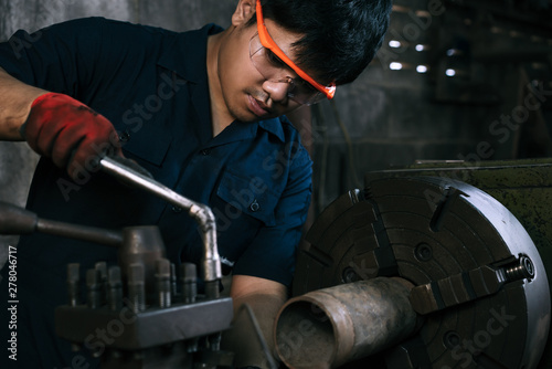 Asian mechanical engineer operating industrial lathe machine - Millennial internship boy training on manufacturing fabrication equipment - Diverse skilled hispanic immigrant factory worker in workshop