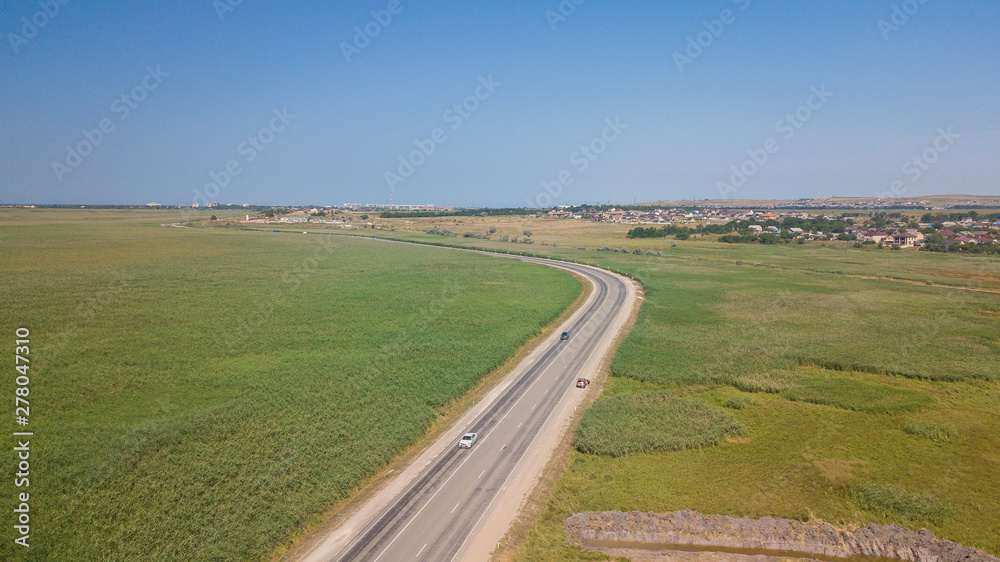 Aerial view of white car driving on country road.
