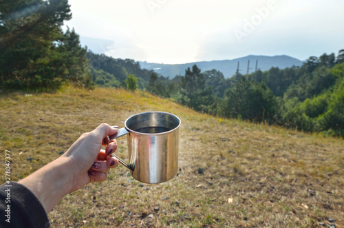 Cup with a hot tea over Beautiful view on mountain and field in summer