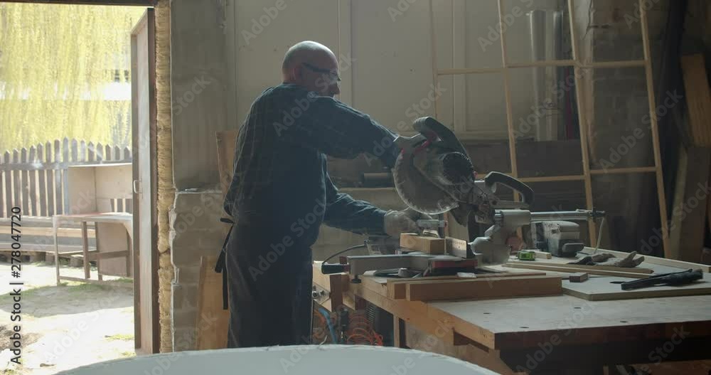 Portrait of male caucasian carpenter carving the wood with headsaw in manufacture. Portrait of male caucasian carpenter carving the wood with headsaw in manufacture.