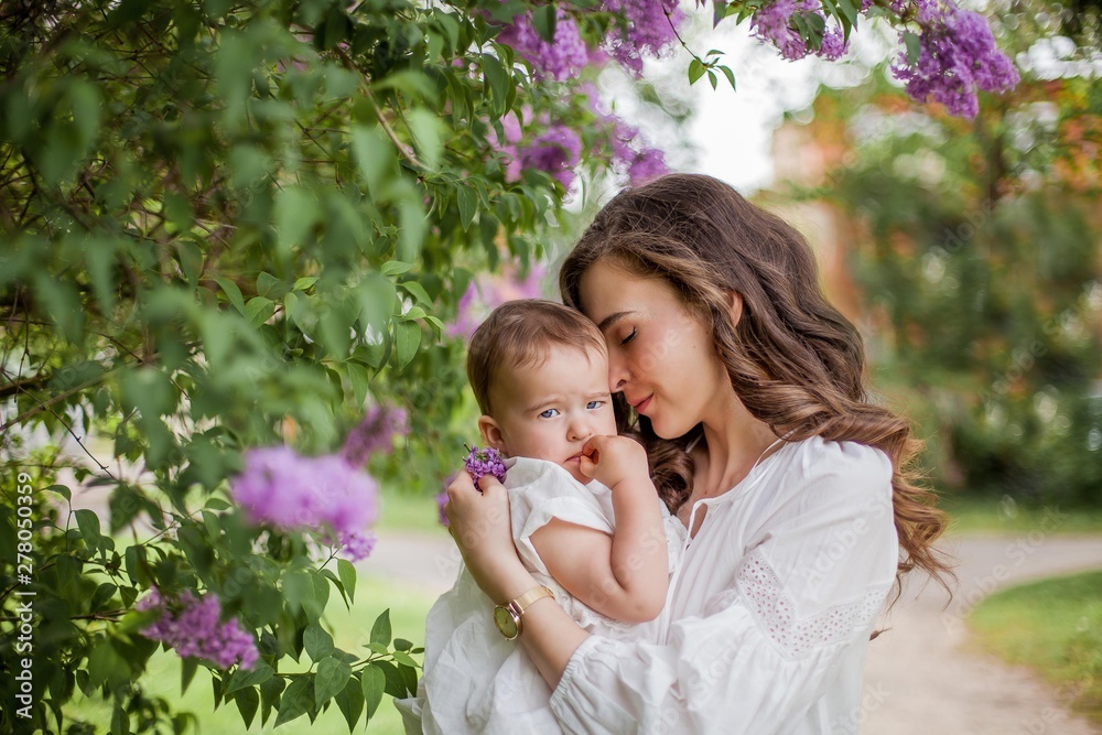 Beautiful young mother and daughter near the blossoming lilac. Spring. Beautiful young mother and daughter near the blossoming lilac. Spring.