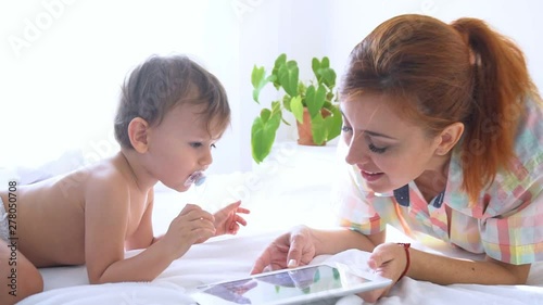 Mom and son look at smartphone on bed