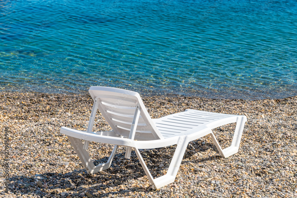 Empty white plastic chaise lounge on the background of the sea Empty white plastic chaise lounge on the background of the sea