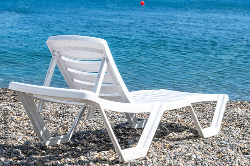 Empty white plastic chaise lounge on the background of the sea