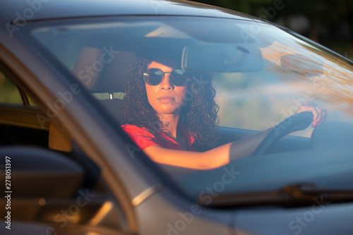 Happy woman driver sitting in car salon at sunset