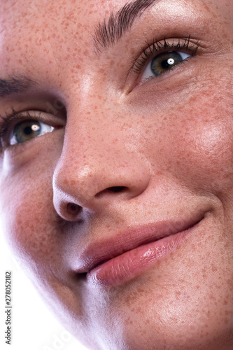 Cute brunette woman with freckles all over her face. Clean flawless fresh skin. Close up beauty concept of skincare and natural make up