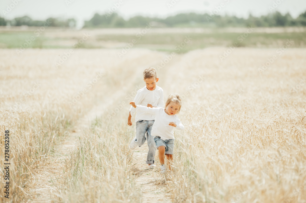 Two happy kids running in wheat field on summer day