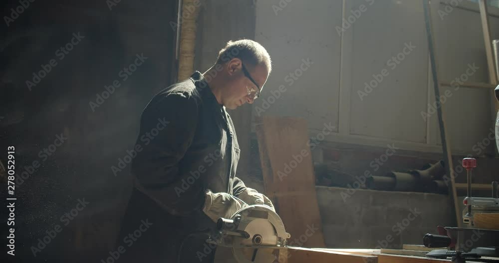 Profile shot of senior male master working at manufacture grinding the wooden board. Profile shot of senior male master working at manufacture grinding the wooden board.