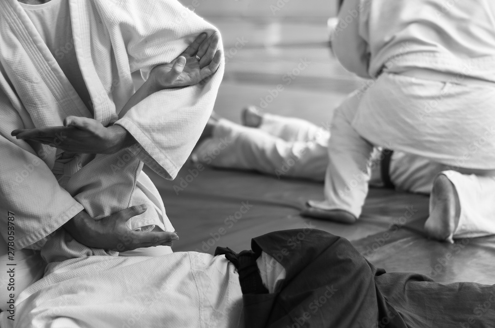 Obraz premium Black and white image of aikido. Hands of fighters. The traditional form of clothing in Aikido. Background image. No faces and recognizable elements
