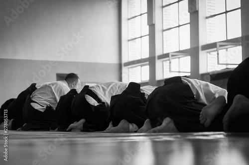 Black and white image of aikido. Men are sporsmen. Aikido workshop. A number of black belt practitioners in traditional uniform, white kimano and black hakama. © Uladzimir