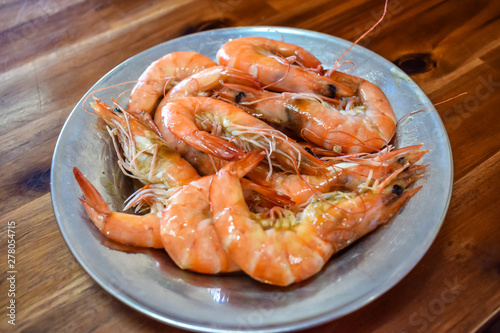 Boiled fresh shrimp on a plate on a wooden table in restaurant