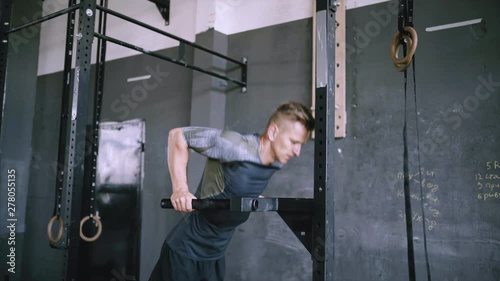 Man does triceps dip exercise in gym on parallel bars or dip stantion. Athlete dressed in comfortable sportswear. Clothes are comfortable and absorb sweat. Muscular man doing bodyweight dips, strength