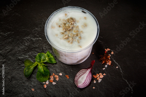 top view of white lard in plastic bowl with basil and onion