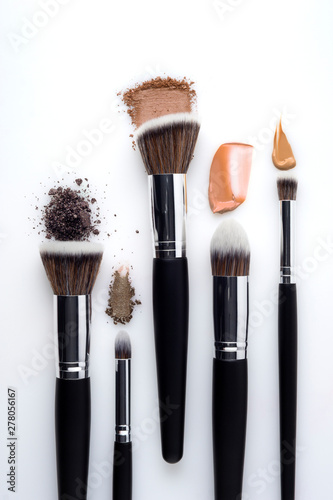 Creative concept beauty fashion photo of cosmetic product make up brushes kit with smashed lipstick eyeshadow on white background.