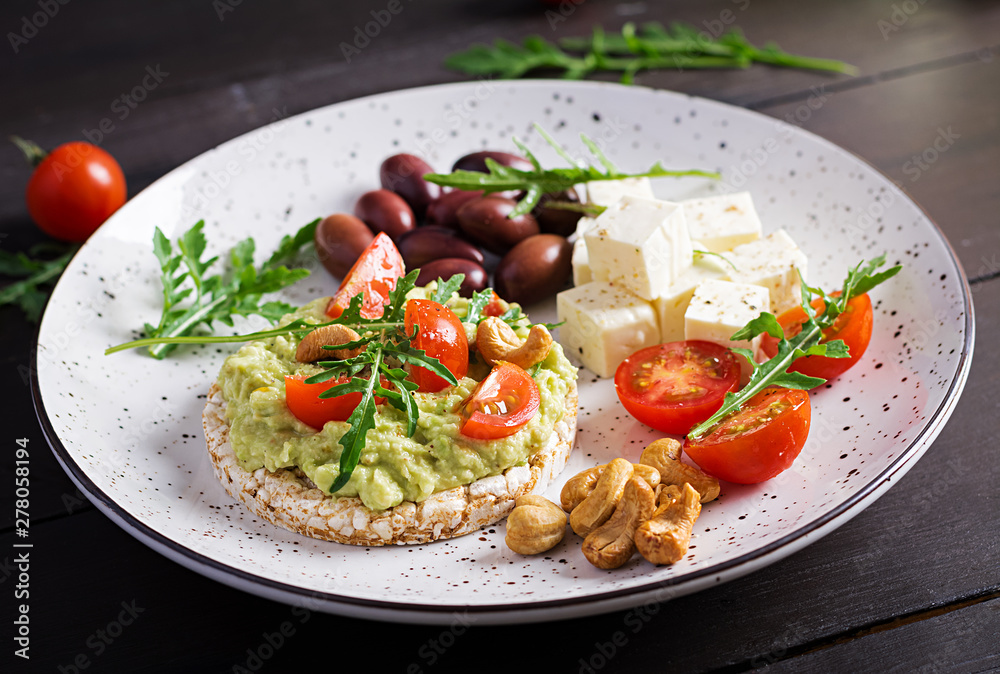 Healthy avocado toasts for breakfast or lunch,  guacamole avocado, kalamata olives, tomatoes, cashew nuts and  feta cheese. Vegetarian sandwiches