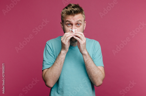 studio picture from a young man with handkerchief. Sick guy isolated has runny nose. man makes a cure for the common cold