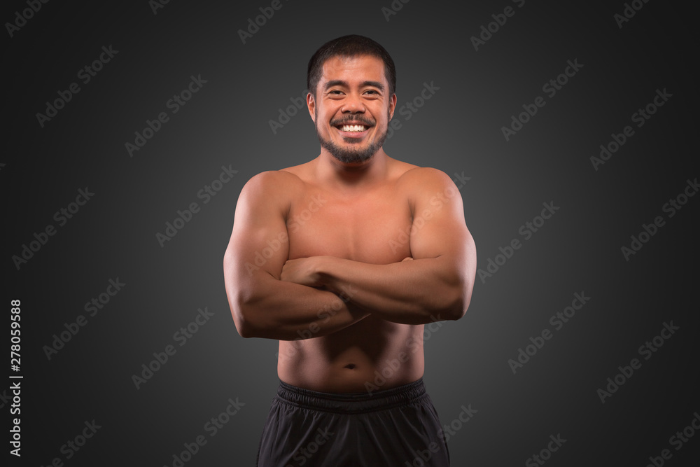 Fototapeta premium Smiling asian man with muscular upper body isolated on grey background. Fitness, workout and training concept.