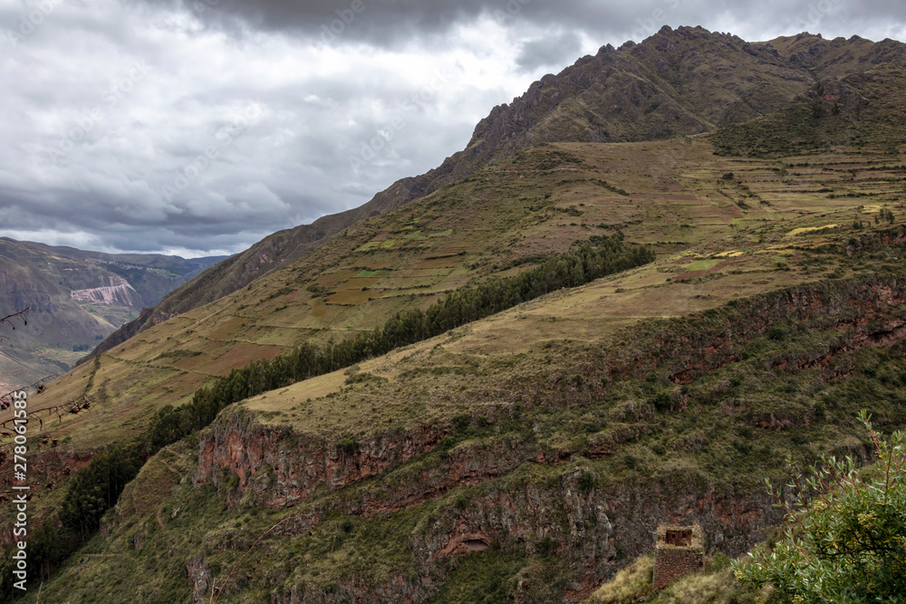 Landscape with green Andean Mountains and Inca ruins on the hiking path in Pisac archeological park, Peru