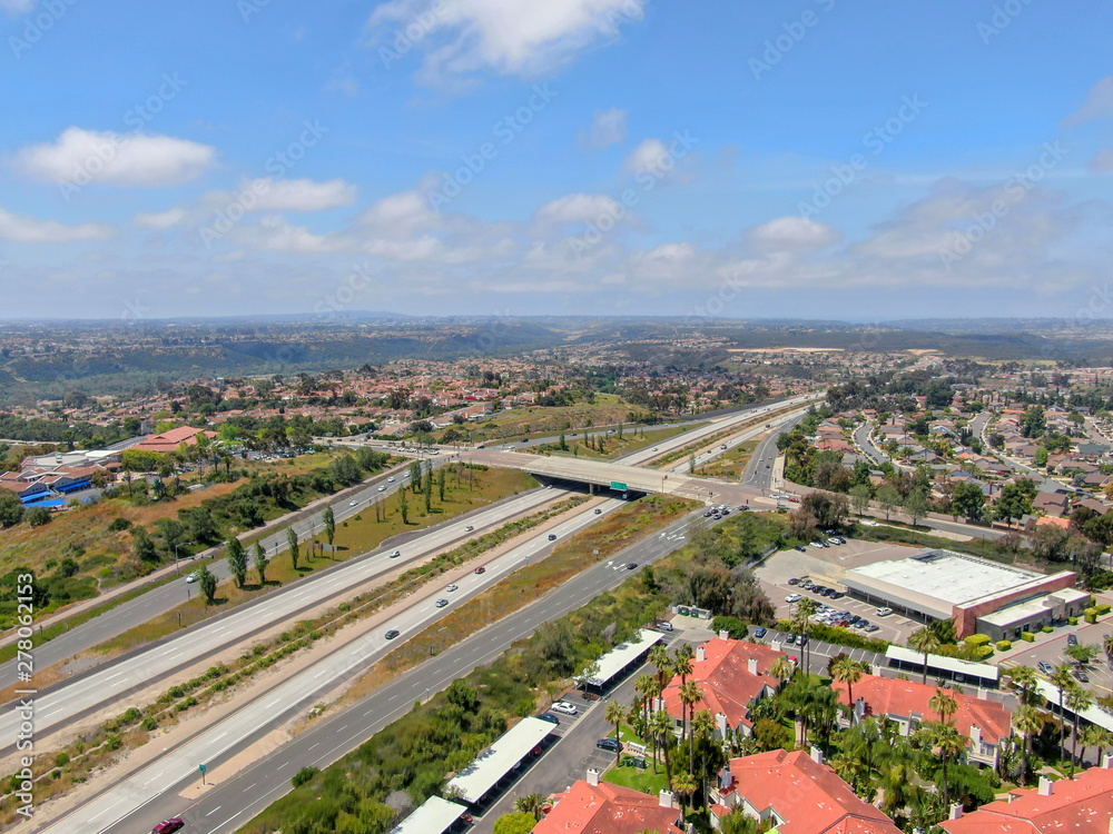 Aerial view of highway surrounded by villa with swimming pool. Intersection city transport road with vehicle movement. California, USA.