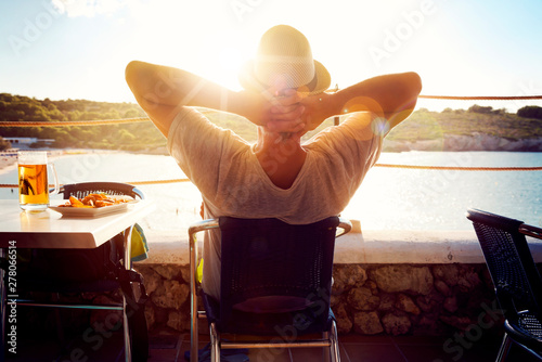 Mann entspannt sich mit Blick auf das Meer und einem Bier