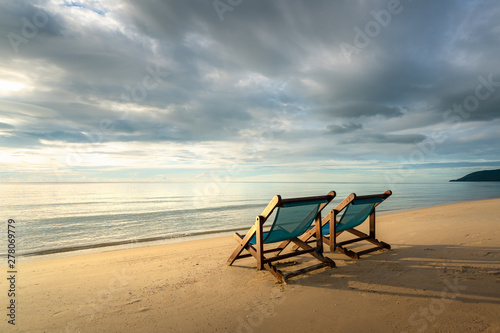 Two deckchairs on the beach at sunset with a tropical sea background. Travel and Vacation in Summer at sea.