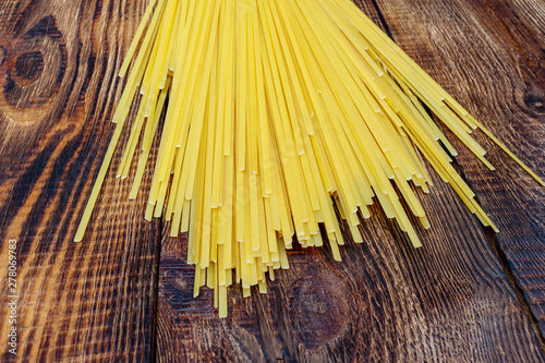 spaghetti, macaroni, pasta, linguine durum wheat Italian thin long on wooden background close up selective focus