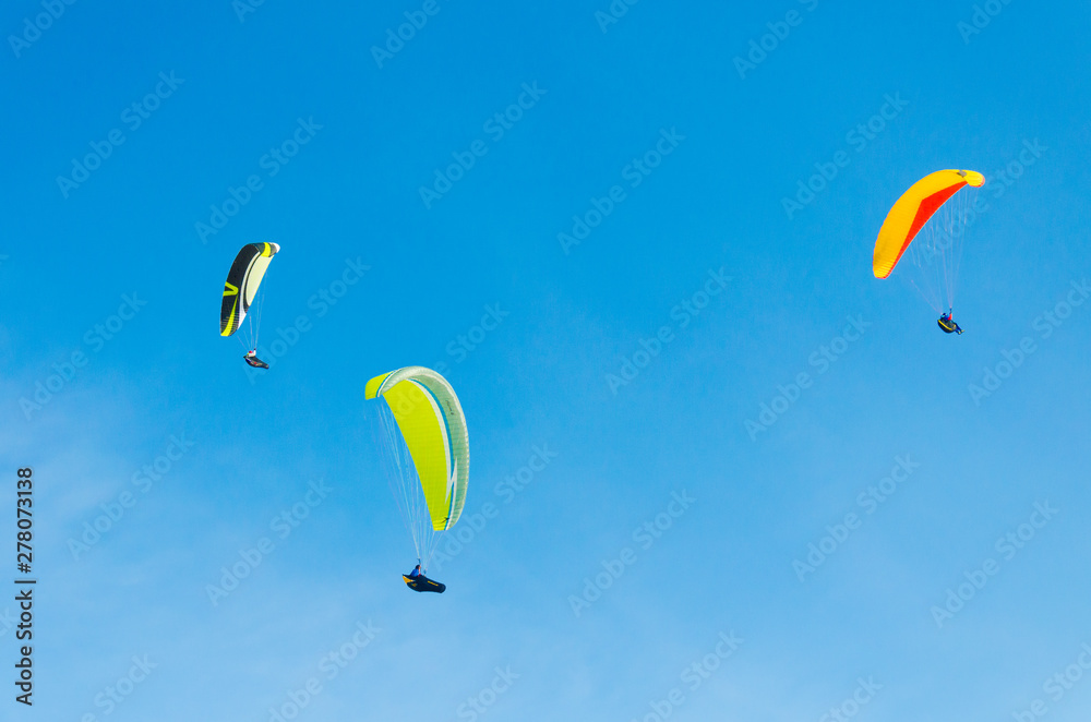 Paragliding in the sky. three paraglider fly over the mountain valley. Competitions with paragliding, Russia, Siberia Paragliding in the sky. three paraglider fly over the mountain valley. Competitions with paragliding, Russia, Siberia