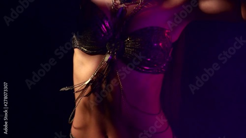 sensual brunette woman is dancing passionately belly dance in dark room, detail view photo