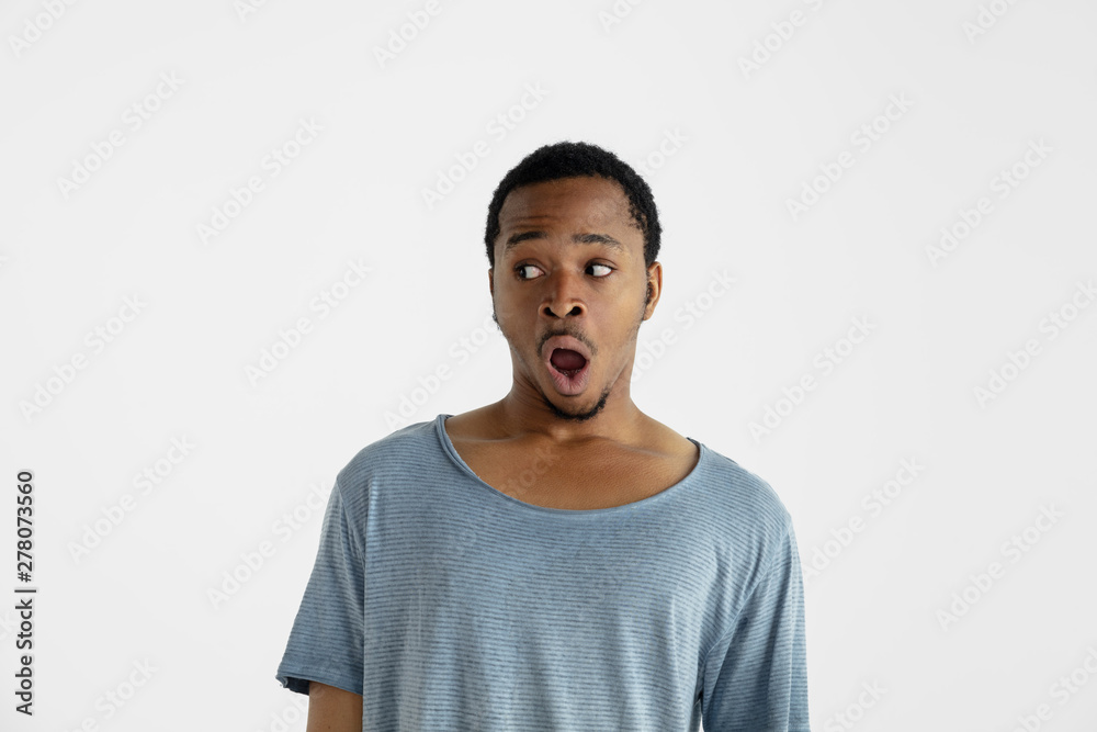 Beautiful male half-length portrait isolated on white studio background. Young emotional african-american man in blue shirt. Facial expression, human emotions, ad concept. Astonished, shocked, crazy Beautiful male half-length portrait isolated on white studio background. Young emotional african-american man in blue shirt. Facial expression, human emotions, ad concept. Astonished, shocked, crazy
