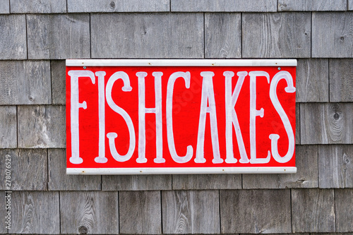 Rustic hand painted seafood sign on a wall of weathered shingles.